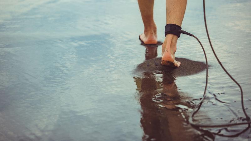 A,Man,Stands,On,The,Beach,With,A,Surfboard.,High